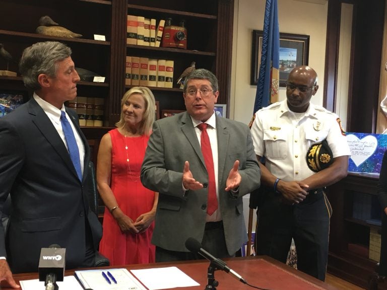 Smyrna School District Superintendent Patrick Williams (third from left)talks about legislation allowing police to inform school leaders when a student experiences a traumatic event. (From left) Gov. John Carney, Lt. Gov. Bethany Hall-Long, and Smryna Police Chief Torrie James stand alongside Williams in Carney’s Dover office. (Mark Eichmann/WHYY)