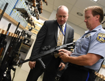 Philadelphia Police Officer Bob Mahan holds a firearm stored in the department's Forensic Science Center beside Michael Garvey, director of the Philadelphia Police Department's Office of Forensic Science (Abdul Sulayman/The Philadelphia Tribune)