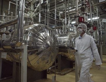 An Iranian security official in protective clothing walks through a uranium conversion facility in 2005. Iran says it is now enriching uranium above the limit set in the 2015 nuclear deal. (Vahid Salemi/AP Photo)