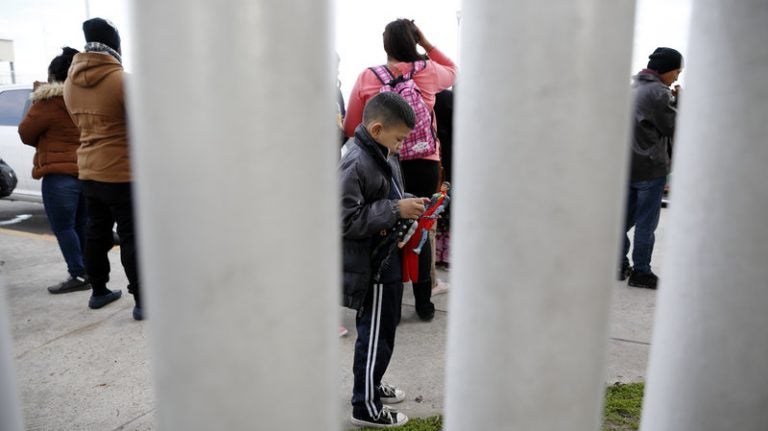 A migrant family waits in Tijuana, Mexico, before being transported to the San Ysidro port of entry to begin the process of applying for asylum in the United States. A new U.S. rule would bar Central American migrants from applying for asylum at the U.S. southern border. (Gregory Bull/AP)