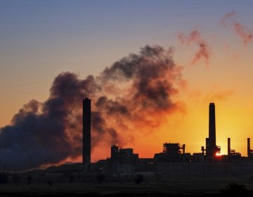 A coal-fired power plant is silhouetted against the morning sun.