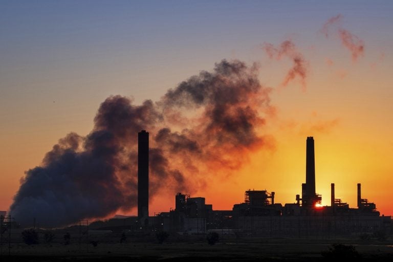 A coal-fired power plant is silhouetted against the morning sun.
