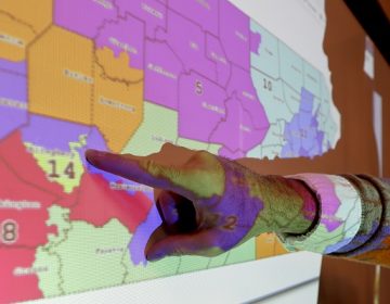 William Marx points out one of the districts that crossed four counties as an image of the old congressional districts of Pennsylvania are projected on a wall in the classroom where he teaches civics in Pittsburgh on Friday, Nov. 16, 2018. (Keith Srakocic/AP Photo)