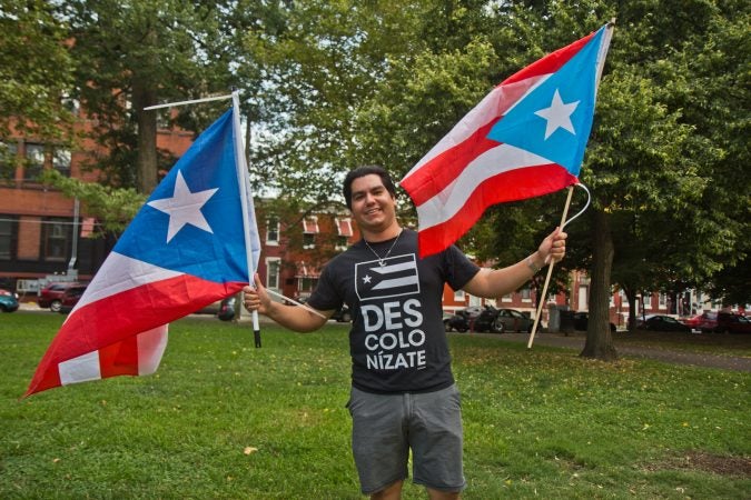 Adrian Mercado flies two Puerto Rican flags at the celebration of the resignation of Puerto Rican governor Ricardo Rosselló at Fairhill Square in Kensington. (Kimberly Paynter/WHYY)