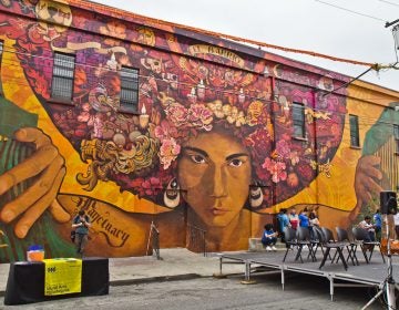 Artists Ian Pierce and Betsy Casañas created “Sanctuary City, Sanctuary Neighborhood,” a mural highlighting immigration issues in society located at 5ht and Huntingdon Streets in North Philadelphia. (Kimberly Paynter/WHYY)