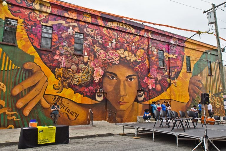 Artists Ian Pierce and Betsy Casañas created “Sanctuary City, Sanctuary Neighborhood,” a mural highlighting immigration issues in society located at 5ht and Huntingdon Streets in North Philadelphia. (Kimberly Paynter/WHYY)