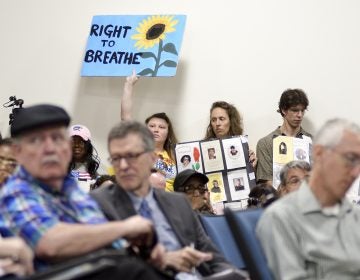 Signs are held up as a standing room only crowd listens to testimony given by environmental experts, community activists and residents during a community meeting regarding the future of the site of Philadelphia Energy Solutions in August 2019. (Bastiaan Slabbers for WHYY)