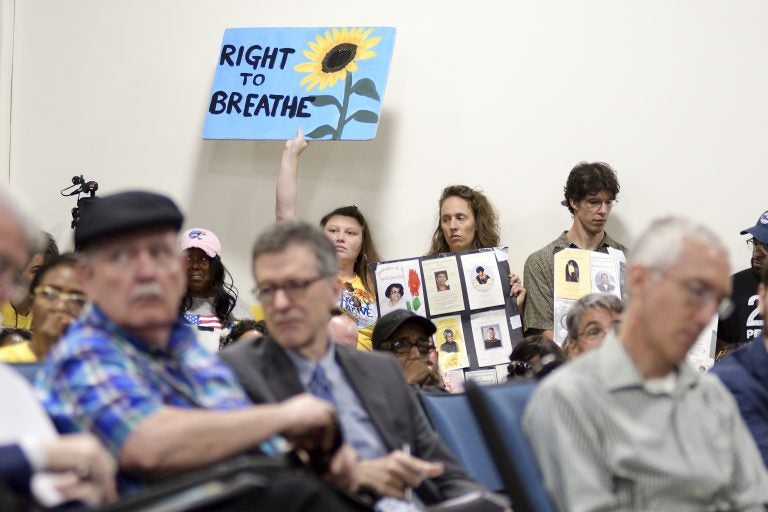 Signs are held up as a standing room only crowd listens to testimony given by environmental experts, community activists and residents during a community meeting regarding the future of the site of Philadelphia Energy Solutions in August 2019. (Bastiaan Slabbers for WHYY)