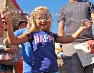 Maura McGlensey, 6, of Clifton Heights, plays with a Slinky during the dedication ceremony of a historical marker commemorating the manufacture of the popular toy at James Industries in Clifton Heights. (Emma Lee/WHYY)