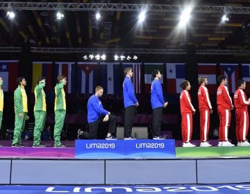 In this Friday, Aug. 9, 2019 photo, released by Lima 2019 News Services, Race Imboden of the United States takes a knee, as teammates Mick Itkin and Gerek Meinhardt stand on the podium after winning the gold medal in team's foil, at the Pan American Games in Lima, Peru. 'Racism, gun control, mistreatment of immigrants, and a president who spreads hate are at the top of a long list' of America's problems, Imboden said in a tweet sent after his medals ceremony. 'I chose to sacrifice my moment today at the top of the podium to call attention to issues that I believe need to be addressed.' (Jose Sotomayor/Lima 2019 News Services via AP)