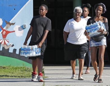 Rahjiah McBride, of Chester, Pa., (right), helps her relatives, Newark residents Elnora and Bowdell Goodwin, center and second right, as Goodwin's son pitches in carrying bottled water from the Boylan Street Recreation Center, Monday, Aug. 12, 2019, in Newark, N.J. (Kathy Willens/AP Photo)