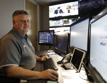 In this July 30, 2019, photo, Paul Hildreth, emergency operations coordinator for the Fulton County School District, works in the emergency operations center at the Fulton County School District Administration Center in Atlanta. Artificial Intelligence is transforming surveillance cameras from passive sentries into active observers that can immediately spot a gunman, alert retailers when someone is shoplifting and help police quickly find suspects. (Cody Jackson/AP Photo)