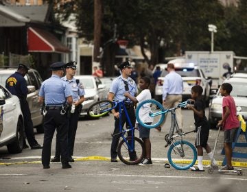 Children visit with officers as officials conduct an investigation at the scene of Wednesday's standoff with police in Philadelphia, Thursday, Aug. 15, 2019. The gunman, identified as Maurice Hill, wounded six police officers before surrendering early Thursday, after an hours-long standoff. (Matt Rourke/AP Photo)