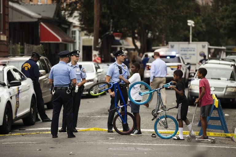 Children visit with officers as officials conduct an investigation at the scene of Wednesday's standoff with police in Philadelphia, Thursday, Aug. 15, 2019. The gunman, identified as Maurice Hill, wounded six police officers before surrendering early Thursday, after an hours-long standoff. (Matt Rourke/AP Photo)