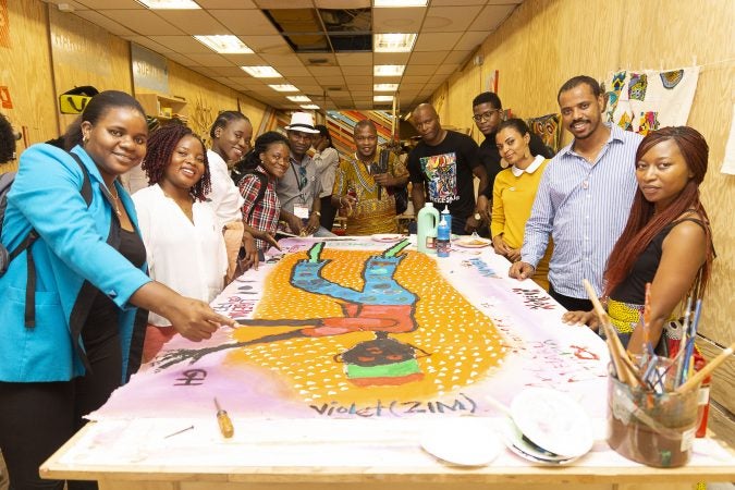 Mandela Washington Fellows pose with Chester Made Artistic Director, Devon Walls (center right), around their group painting of an African Stilt Walker created during the Chester Made and Mandela Washington Fellowship Exchange 2019. (Greg Irvin)