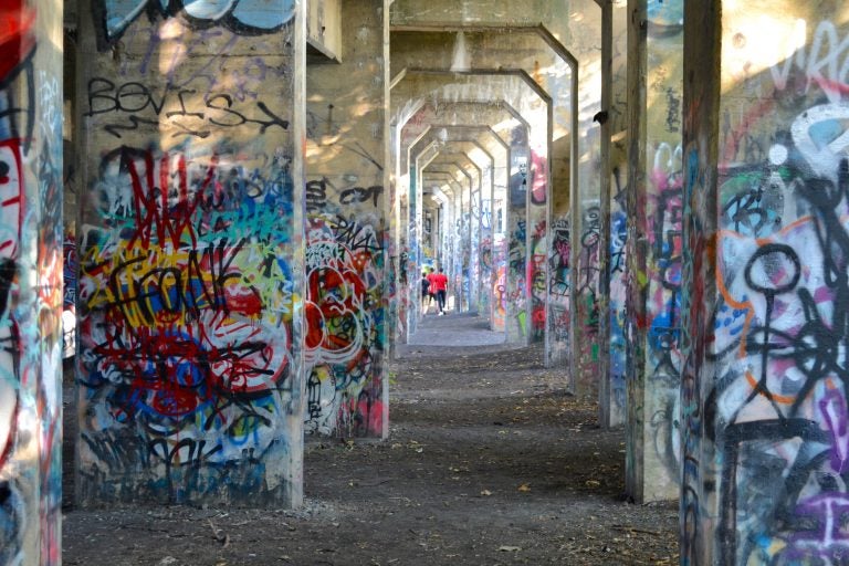 Visitors walk under the arches of Graffiti Pier. (Joel Wolfram for WHYY)