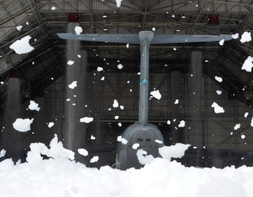 Wind-blown clumps of fire-suppression foam hang in the air outside of hangar 706 while the tail of a massive C-5M Super Galaxy can be seen inside the hangar at Dover Air Force Base, Del. (U.S. Air Force photo/Greg L. Davis)