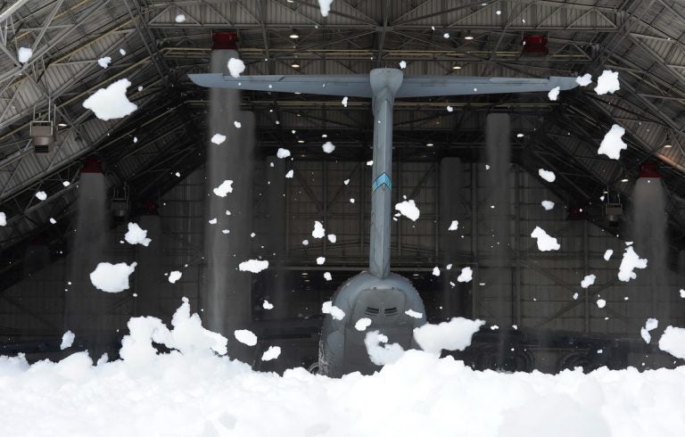 Wind-blown clumps of fire-suppression foam hang in the air outside of hangar 706 while the tail of a massive C-5M Super Galaxy can be seen inside the hangar at Dover Air Force Base, Del. (U.S. Air Force photo/Greg L. Davis)