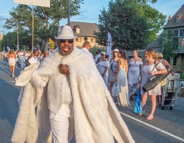 Participants in Philadelphia's 8th annual Dîner en Blanc make their way down Kelly Drive past Boathouse Row. Guests came in a range of attire from understated to outrageous, but all came in white. (Jonathan Wilson for WHYY)