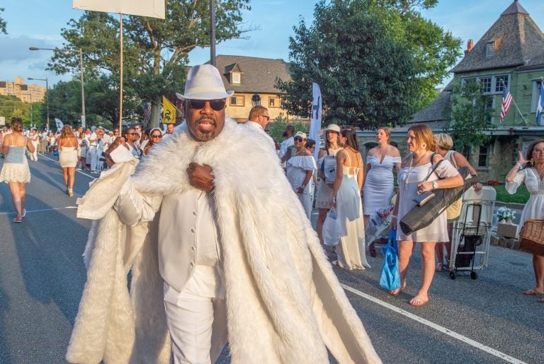 Participants in Philadelphia's 8th annual Dîner en Blanc make their way down Kelly Drive past Boathouse Row. Guests came in a range of attire from understated to outrageous, but all came in white. (Jonathan Wilson for WHYY)