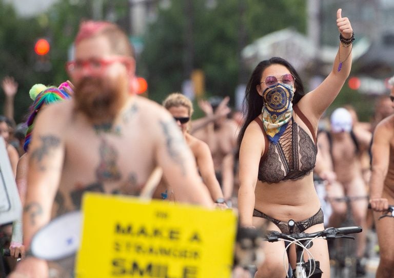 A rider gives a thumbs up to a cheering crowd during the Philly Naked Bike Ride. (Jonathan Wilson for WHYY)