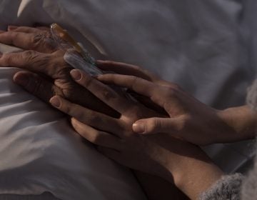 Photo of woman holding terminally ill mother hand