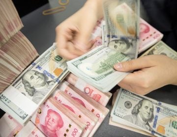 A Chinese bank employee counts 100-yuan notes and dollar bills at a counter in Nantong, in China's eastern Jiangsu province, on Tuesday. (AFP/Getty Images)