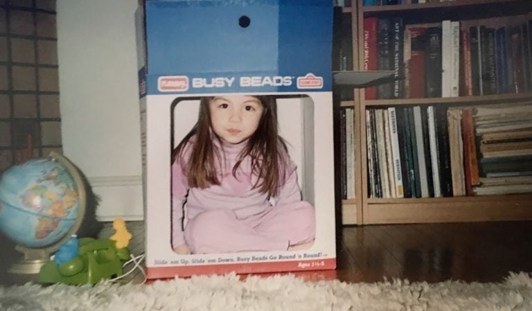 Liz Tung, at 3 years old, pretends to be on television using a cardboard box. (Image courtesy of Liz Tung)