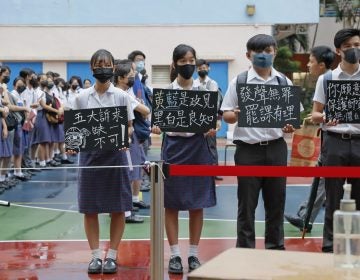 High school students wearing masks, hold placards which read 