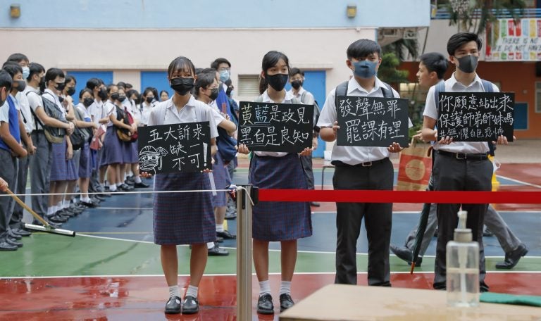 High school students wearing masks, hold placards which read 