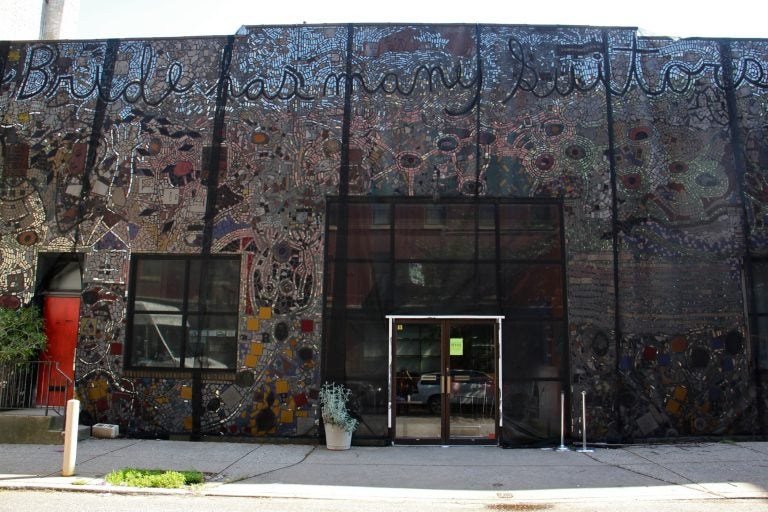 The Painted Bride Art Center is draped in black mesh since it was discovered that the Isaiah Zagar mural that covers it is separating from its walls. (Emma Lee/WHYY)