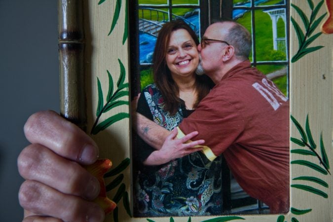 Joanne Schilk-Bierman holds a framed photo from a visits to her brother oldest brother Tom Schilk, who’s serving a lift sentence in prison. (Kimberly Paynter/WHYY)