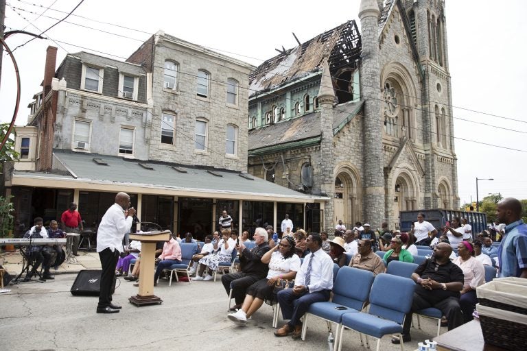 Bishop Benjamin Peterson Jr. (left) leads Sunday morning services outside of the damaged Greater Bible Way Temple on Sept. 1, 2019. (Rachel Wisniewski for WHYY)