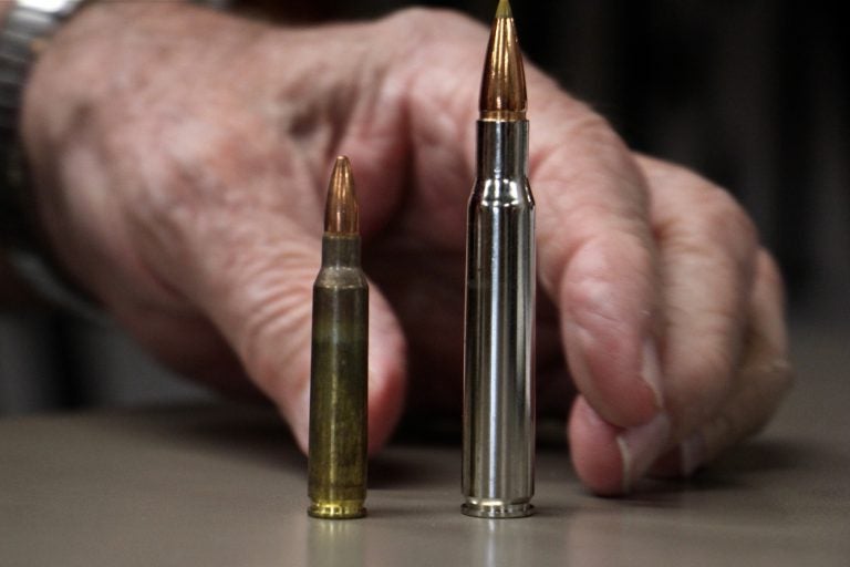 Bob Viden, owner of Bob's Little Sport Shop in Glassboro N.J., compares the bullets used in the AR 15 (left) and the Remmington hunting rifle. (Emma Lee/WHYY)