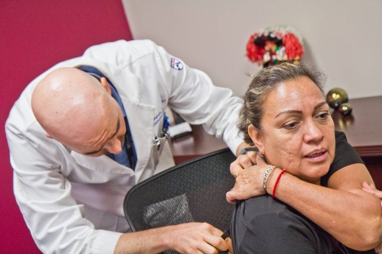 Dr. Cory Simpson, dermatologist, screens Diocelina Zabalo for skin cancer at Philadelphia’s Mexican consulate. (Kimberly Paynter/WHYY)