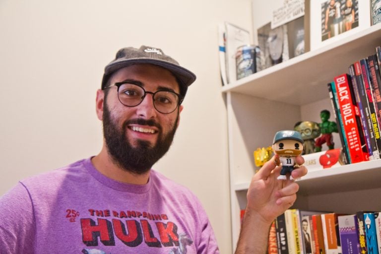 Shamus Clancy, Philadelphia writer and sports super fan, shows off his Carson Wentz bobble head toy at his apartment in South Philly. (Kimberly Paynter/WHYY)