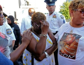 Sonya Dixon (center), whose two grandsons were murdered in 2017 and 2018, weeps during a demonstration outside the Philadelphia Police headquarters to call attention to unsolved murders. (Emma Lee/WHYY)