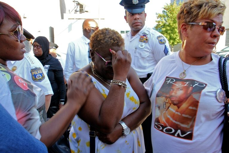 Sonya Dixon (center), whose two grandsons were murdered in 2017 and 2018, weeps during a demonstration outside the Philadelphia Police headquarters to call attention to unsolved murders. (Emma Lee/WHYY)