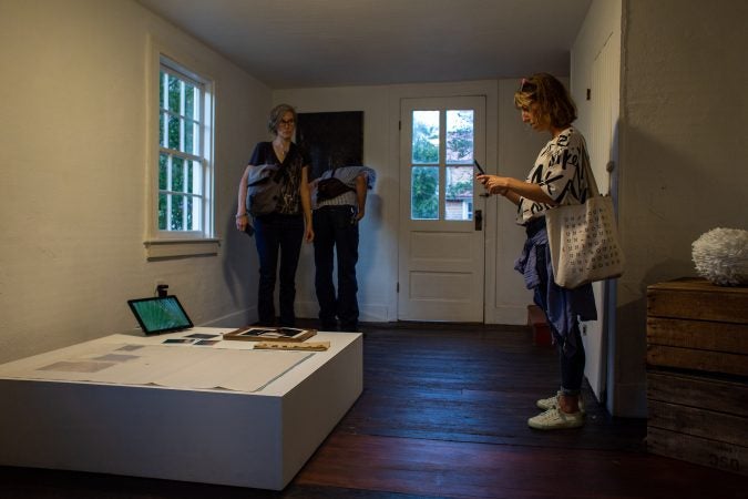 Nike Desis (right) of New London, Connecticut, photographs one of the art pieces curated for 