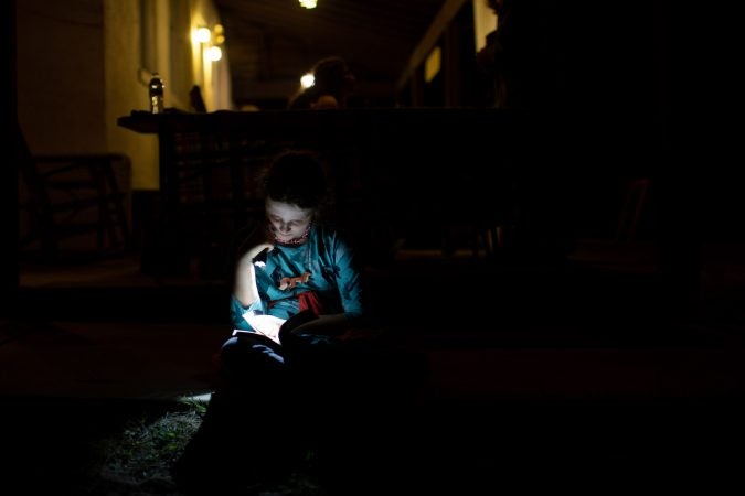 A girl reads by flashlight at 