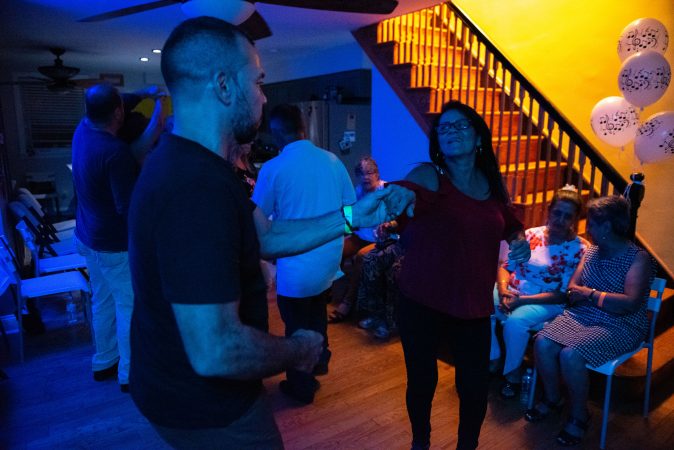 Guests dance to latin music in a living room-turned-viejoteca in Oxford Circle on Saturday, September 14, 2019. (Kriston Jae Bethel for WHYY)