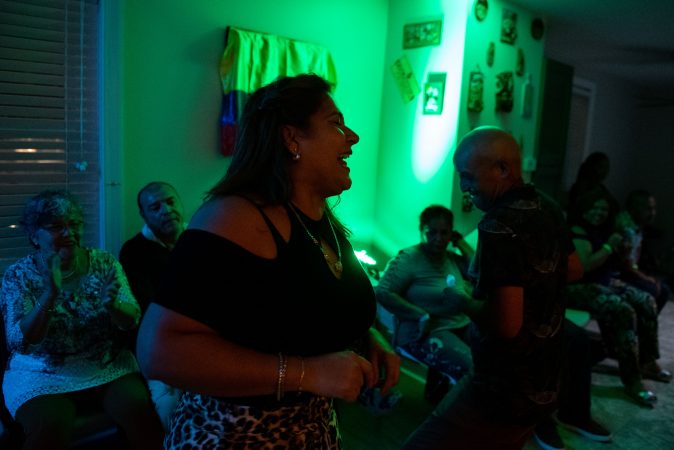 Sandra Colon laughs while dancing in the living room of her Oxford Circle home on Sunday, September 15, 2019. Colon regularly turns her home into a viejoteca (a dance party for older adults) after one restaurant in Philadelphia that hosted them closed down. (Kriston Jae Bethel for WHYY)