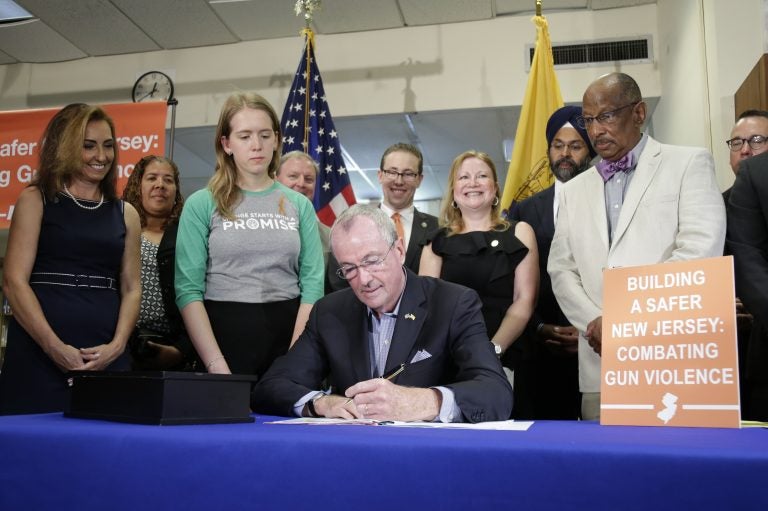 New Jersey Gov. Phil Murphy, center, signs a gun control bill during a ceremony in Berkeley Heights, N.J., Tuesday, July 16, 2019. (AP Photo/Seth Wenig)
