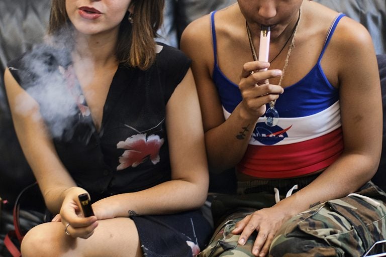 two women smoke cannabis vape pens at a party in Los Angeles.