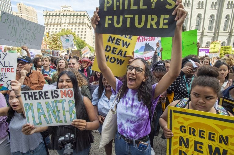 Masterman High School seniors Iman Acharya and Alina Kilcullen cheer for speakers at Philadelphia's climate strike on Sept. 20, 2019. (Jonathan Wilson for WHYY)