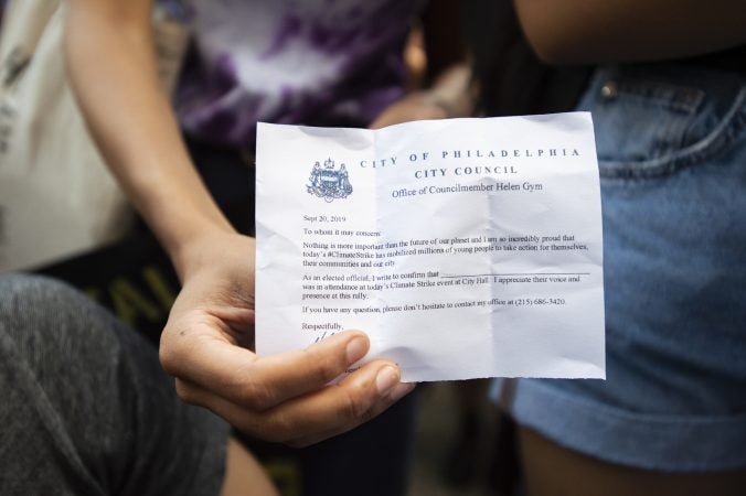 A student holds an school absentee excuse notice from Councilmember Helen Gym. (Jonathan Wilson for WHYY)