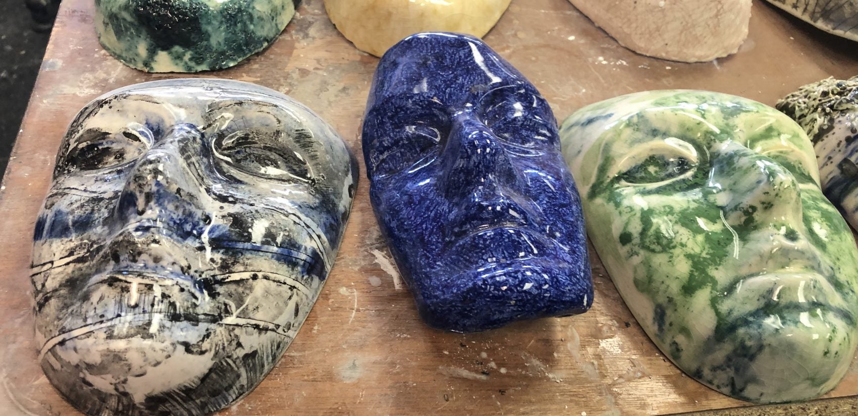 Ceramic faces fill a table in the sculpting studio. (Cris Barrish/WHYY)