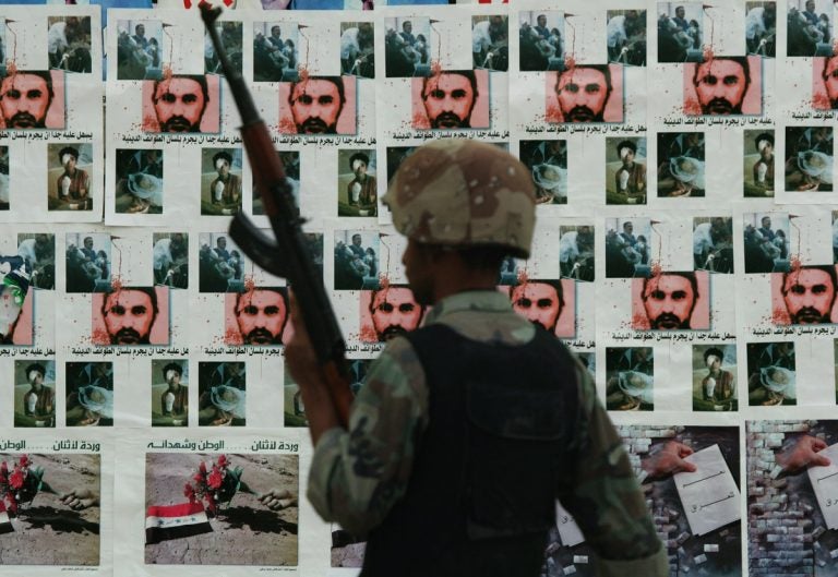 In this Dec. 16, 2005 photo, an Iraqi soldier guards at a checkpoint backdropped with posters, some are pictures of terror leader Abu Musab al-Zarqawi, in Baghdad, Iraq. (AP Photo/Hadi Mizban)