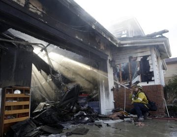 Calib Willis of the Los Angeles County Fire Department hoses down a smoldering residence destroyed by a wildfire Friday, Oct. 25, 2019, in Santa Clarita, California. (Marcio Jose Sanchez/AP Photo)