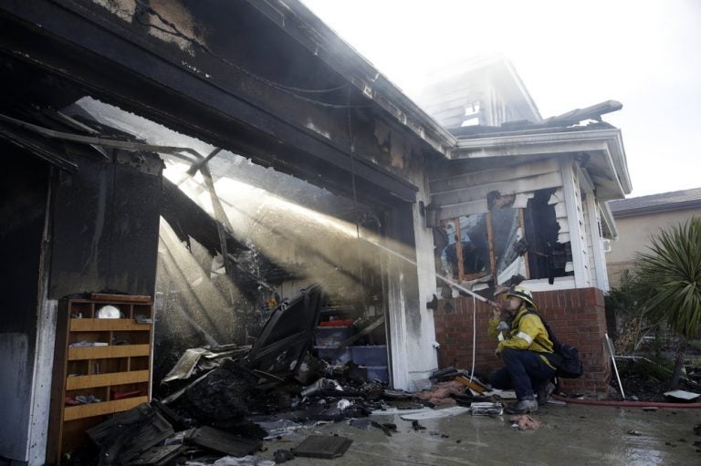 Calib Willis of the Los Angeles County Fire Department hoses down a smoldering residence destroyed by a wildfire Friday, Oct. 25, 2019, in Santa Clarita, California. (Marcio Jose Sanchez/AP Photo)